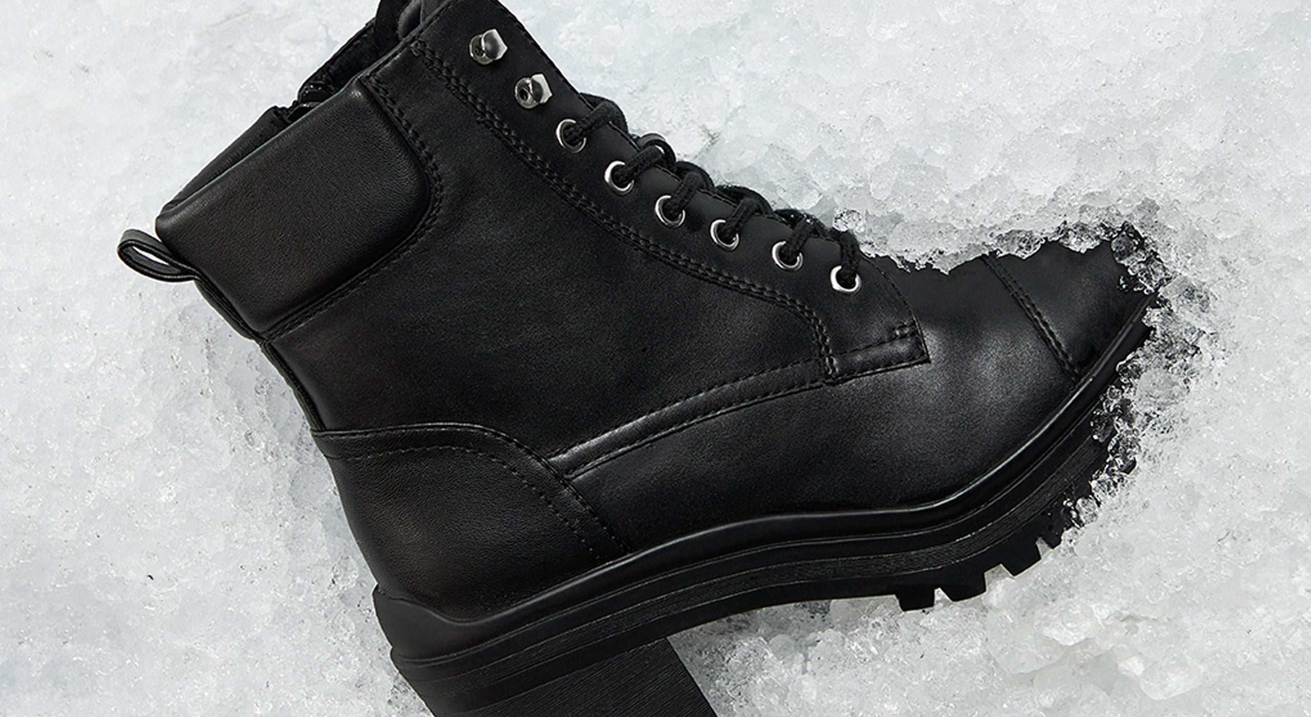 Black leather boot on a snowy ground.