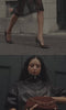 A video of a woman walking down the street in a brown jacket and brown pump heels, carrying a matching brown suede clutch for an effortlessly polished look.